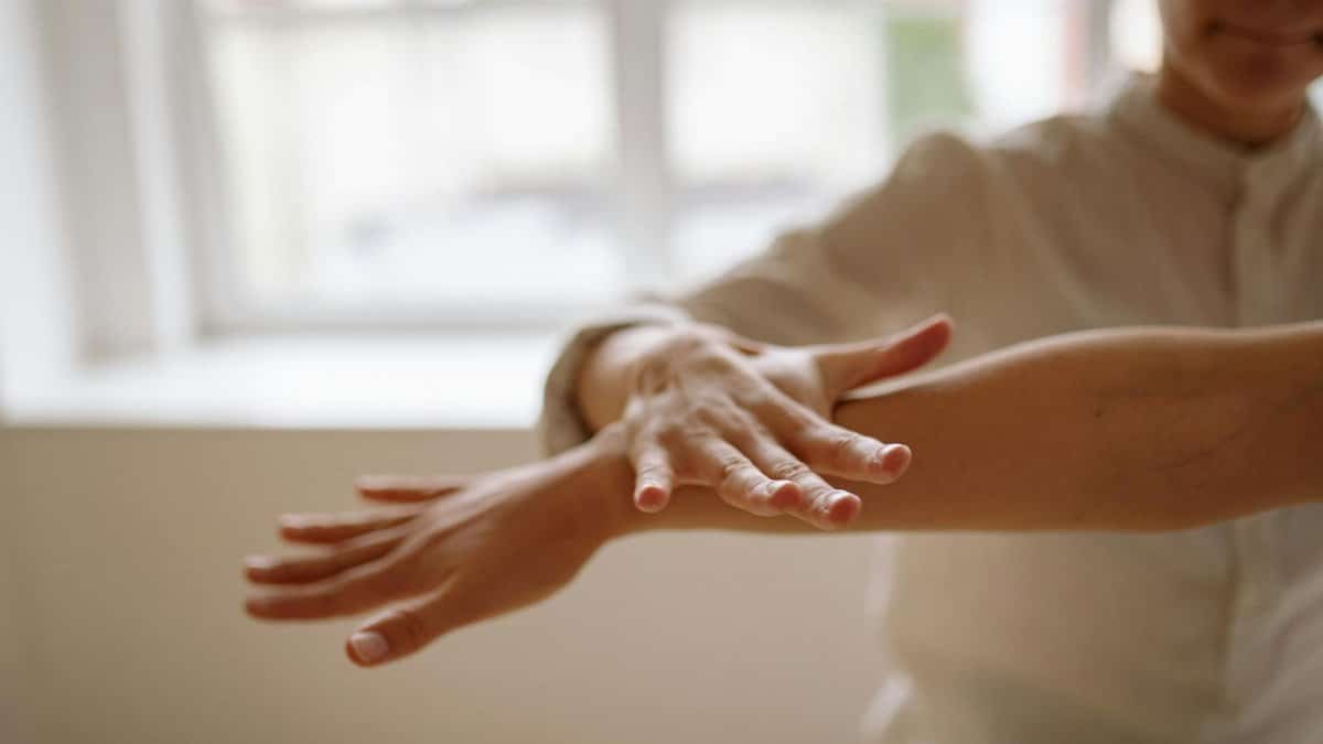 A close-up view of a person using a relaxation technique with hands in motion, in a bright, airy space.