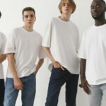 A group of four diverse men modeling white t-shirts and jeans in a studio setting.