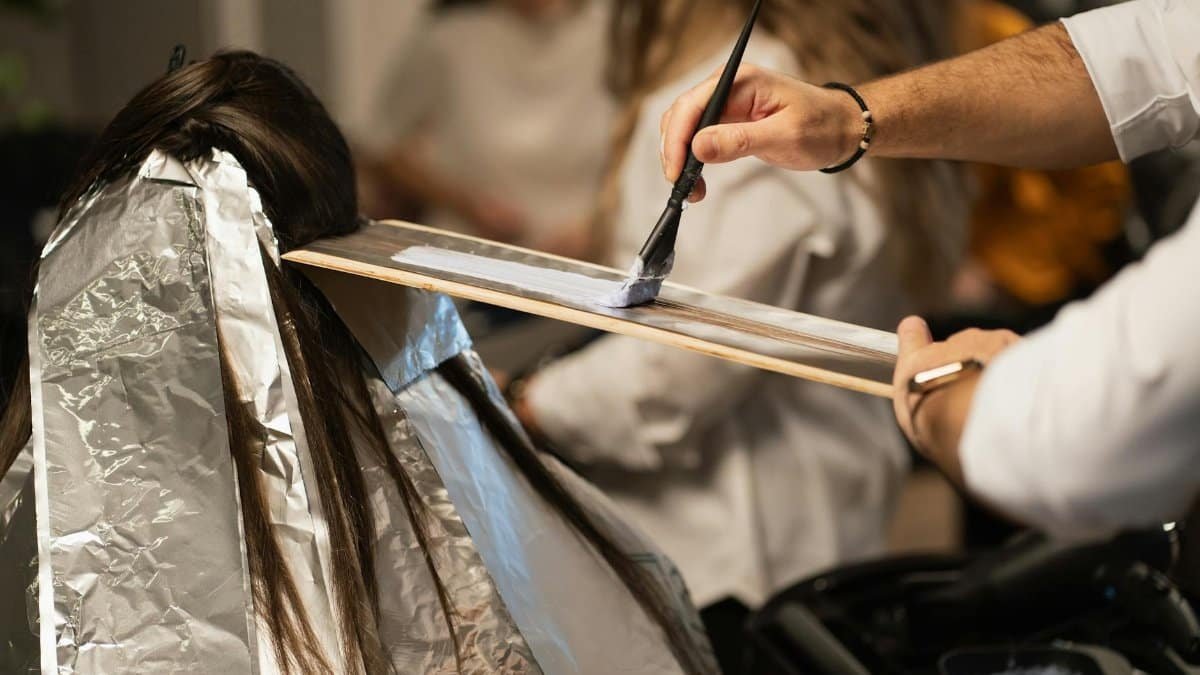 Hairdresser applying dye to client's hair with precision, showcasing modern salon hair coloring techniques.
