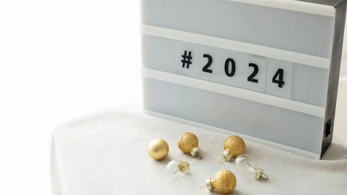 A stylish New Year 2024 decoration with gold baubles and a lightbox on a white tablecloth.