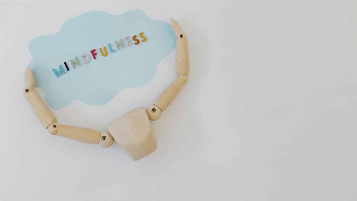 Wooden mannequin holding a mindfulness speech bubble for relaxation and mental health concepts.