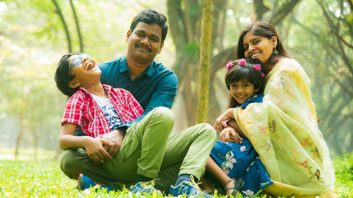 Cheerful family sitting on the grass, enjoying time outdoors together in a serene park.