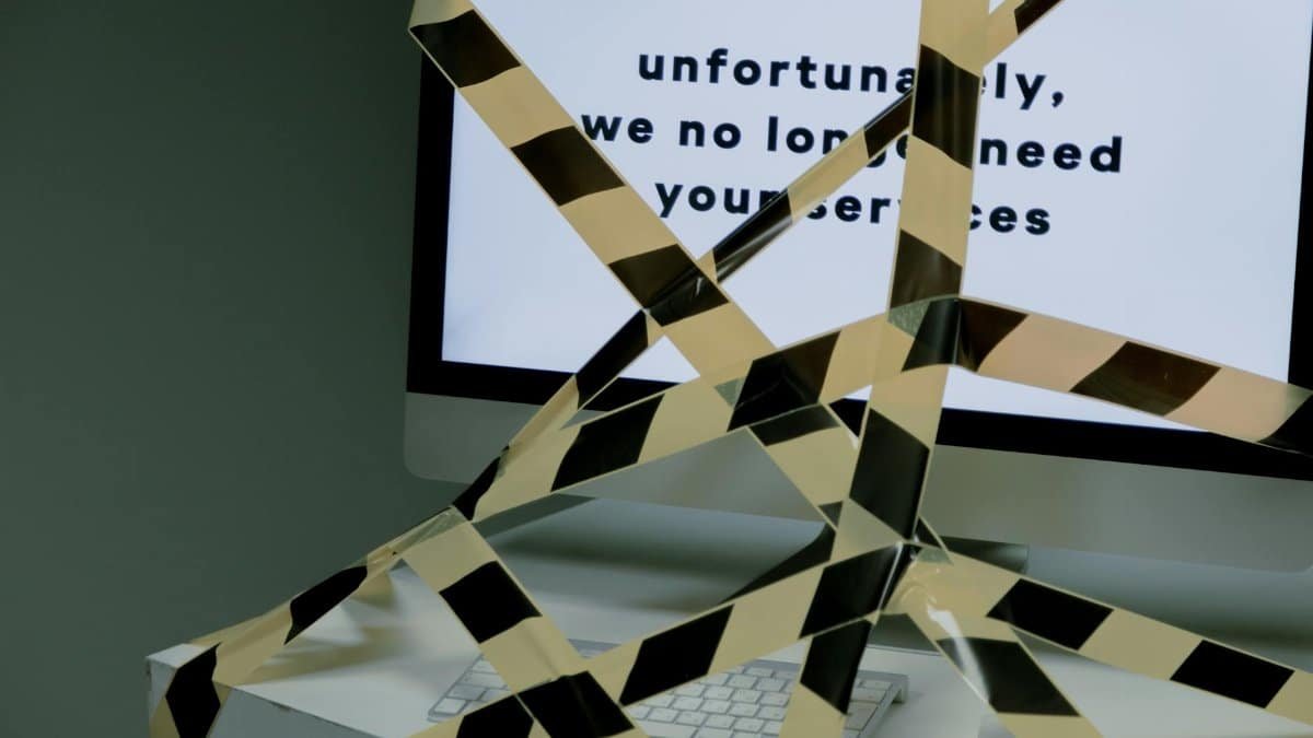 A computer screen taped and displaying a termination message, symbolizing unemployment.