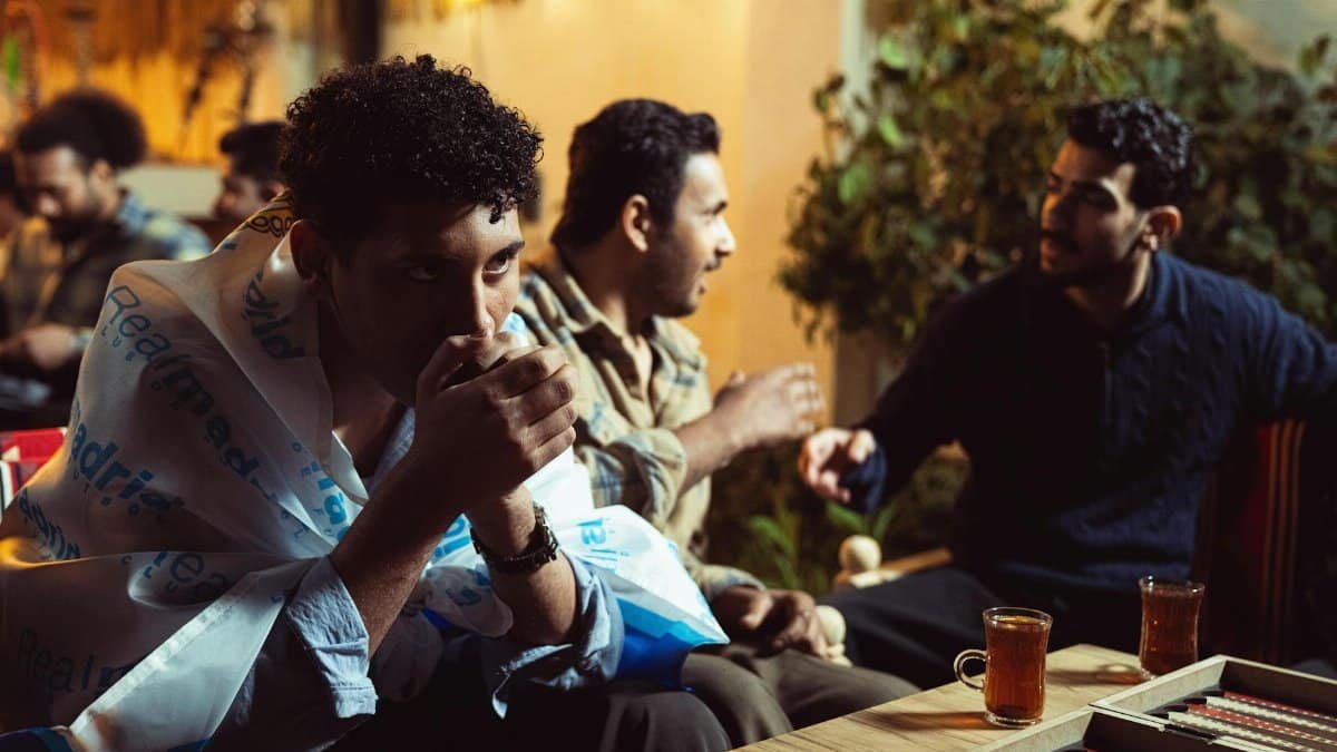 People enjoying tea and conversation in a cozy indoor setting with warm lighting.