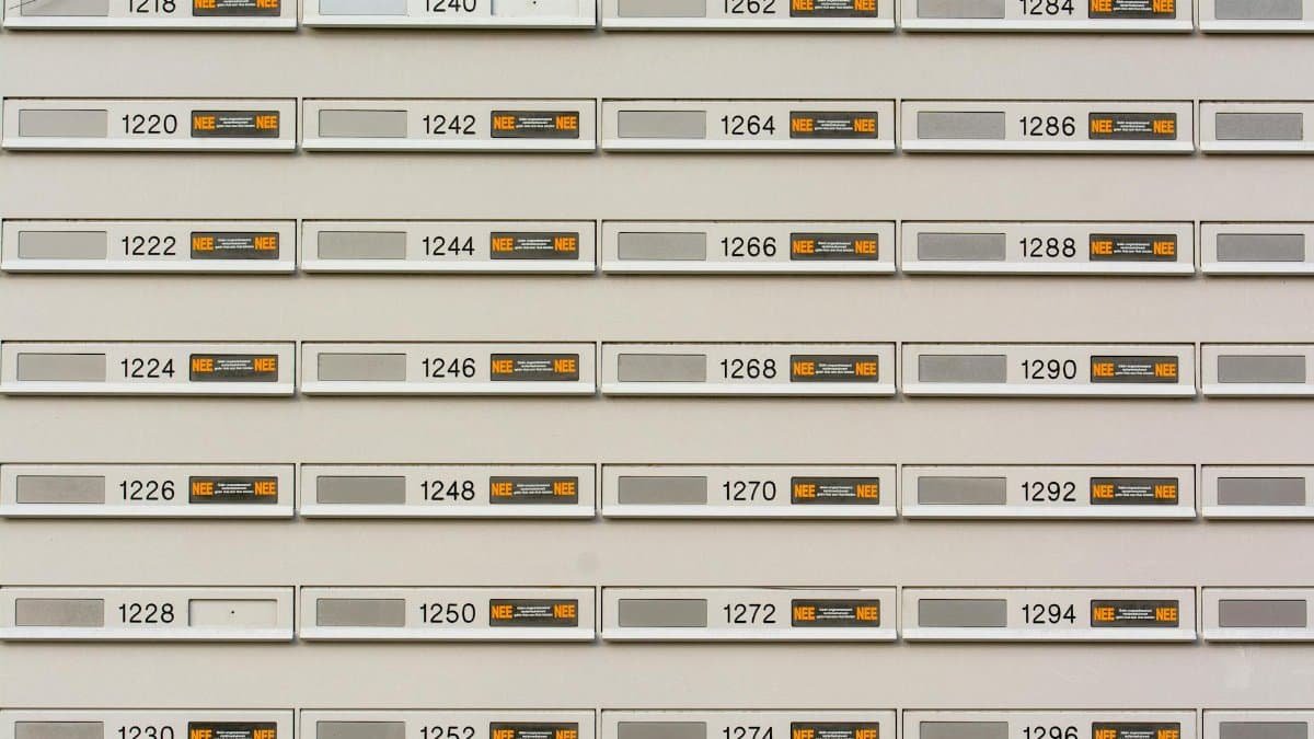 Row of modern mailboxes with numbers in an urban setting, featuring a pattern.