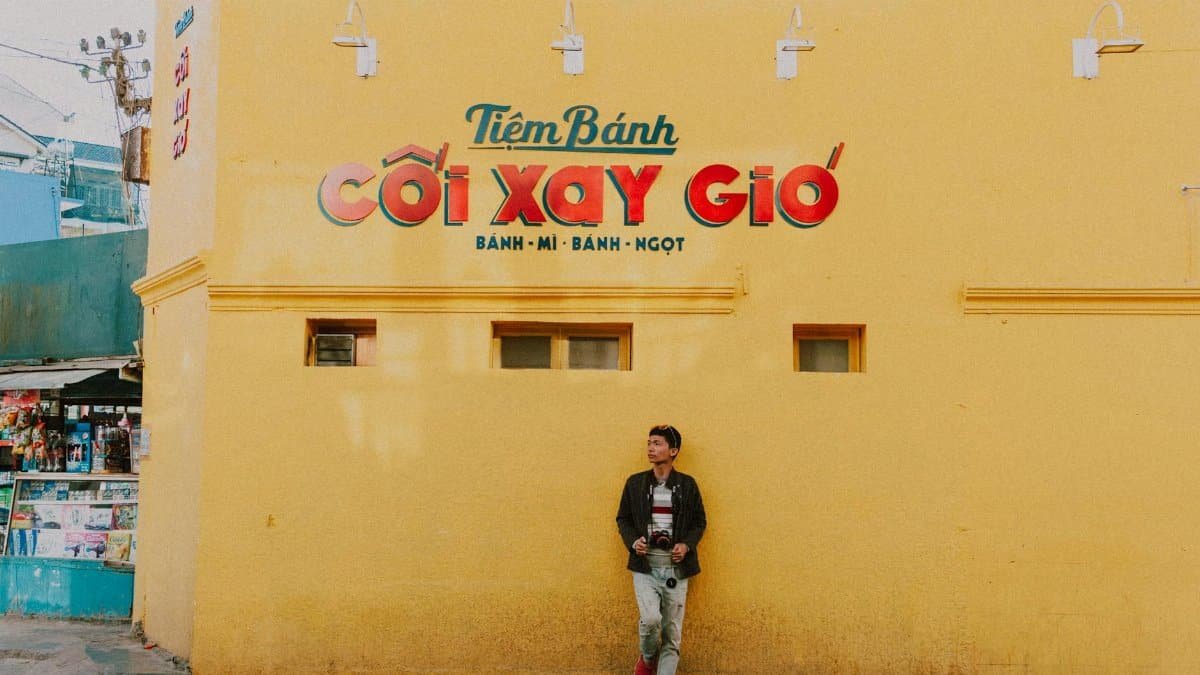 A man stands against a vibrant yellow wall in Vietnam, capturing the urban essence.