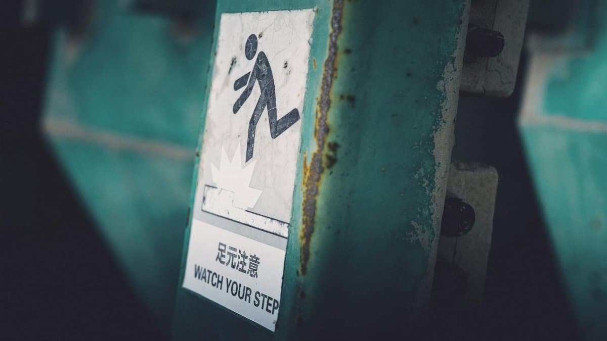 Dimly lit caution sign indicating 'Watch Your Step' in urban setting.