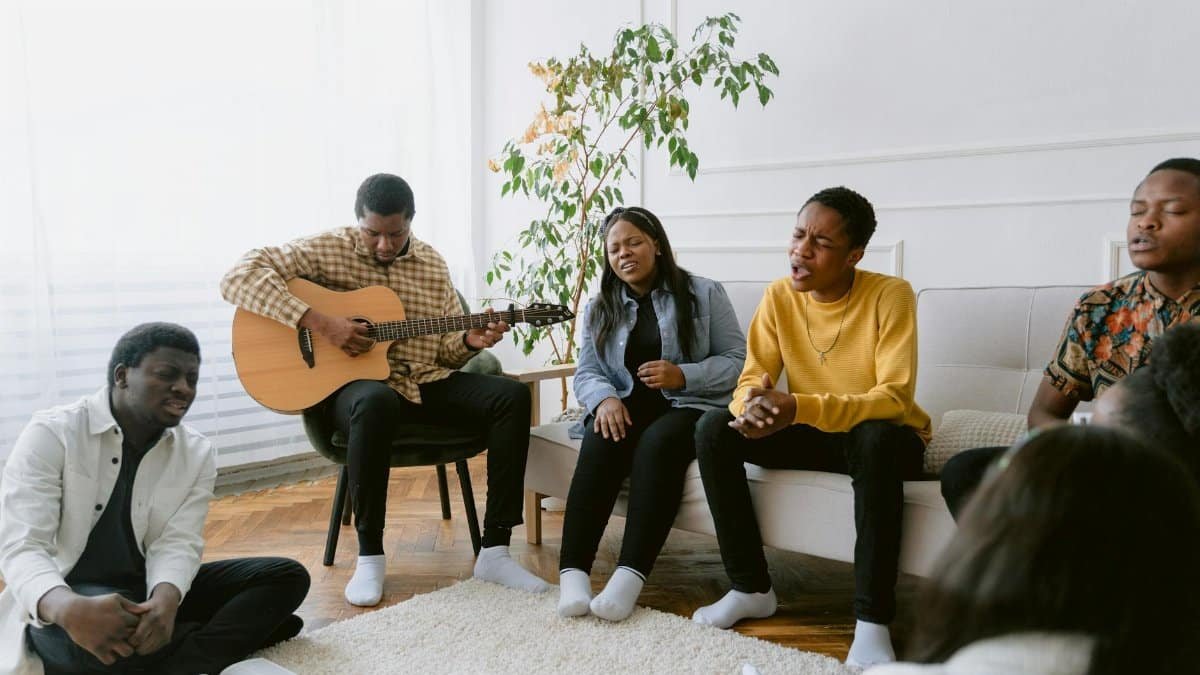 A group of friends singing and playing guitar together in a cozy indoor setting.