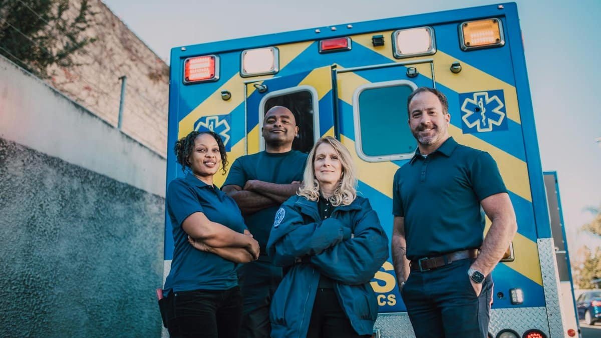 Paramedic team stands confidently in front of an ambulance, ready for emergencies.