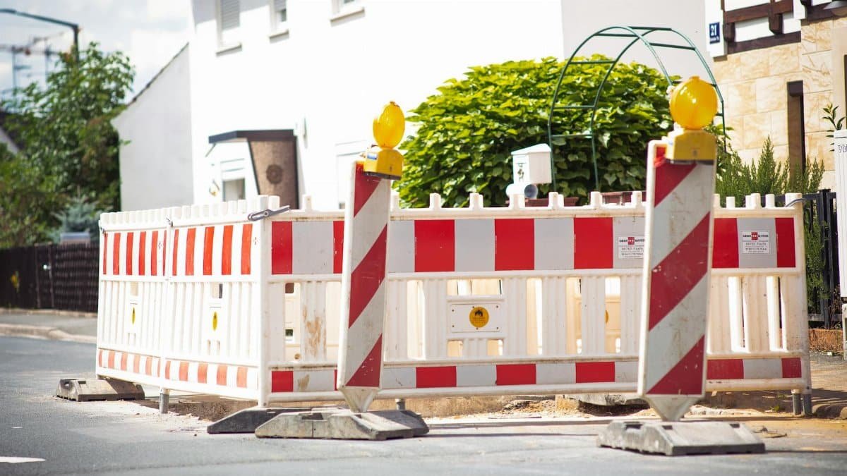 Bright road barrier with striped pattern signals construction on suburban street.