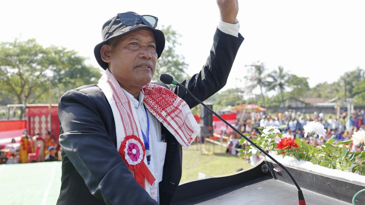 An Asian man giving a speech at an outdoor rally, gesturing with his hand.