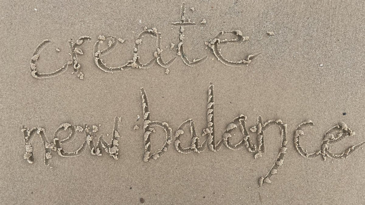Sand writing 'create new balance' on a Scottish beach, symbolizing fresh starts and harmony.