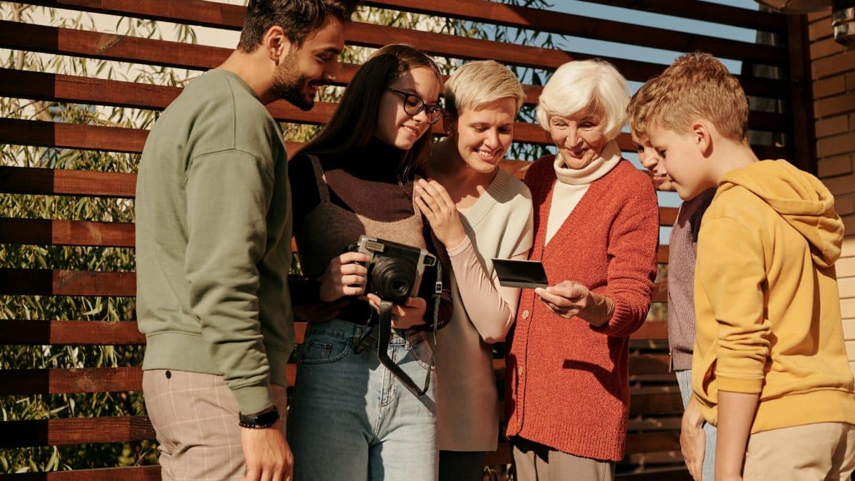 A family of various ages sharing a joyful moment outdoors with a vintage camera.