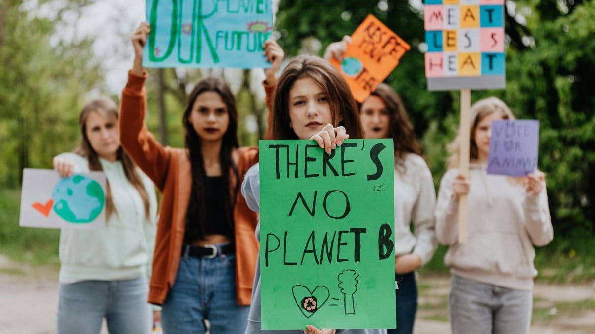 Group of young women protesting for climate change with signs outdoors. Environmental activism theme.