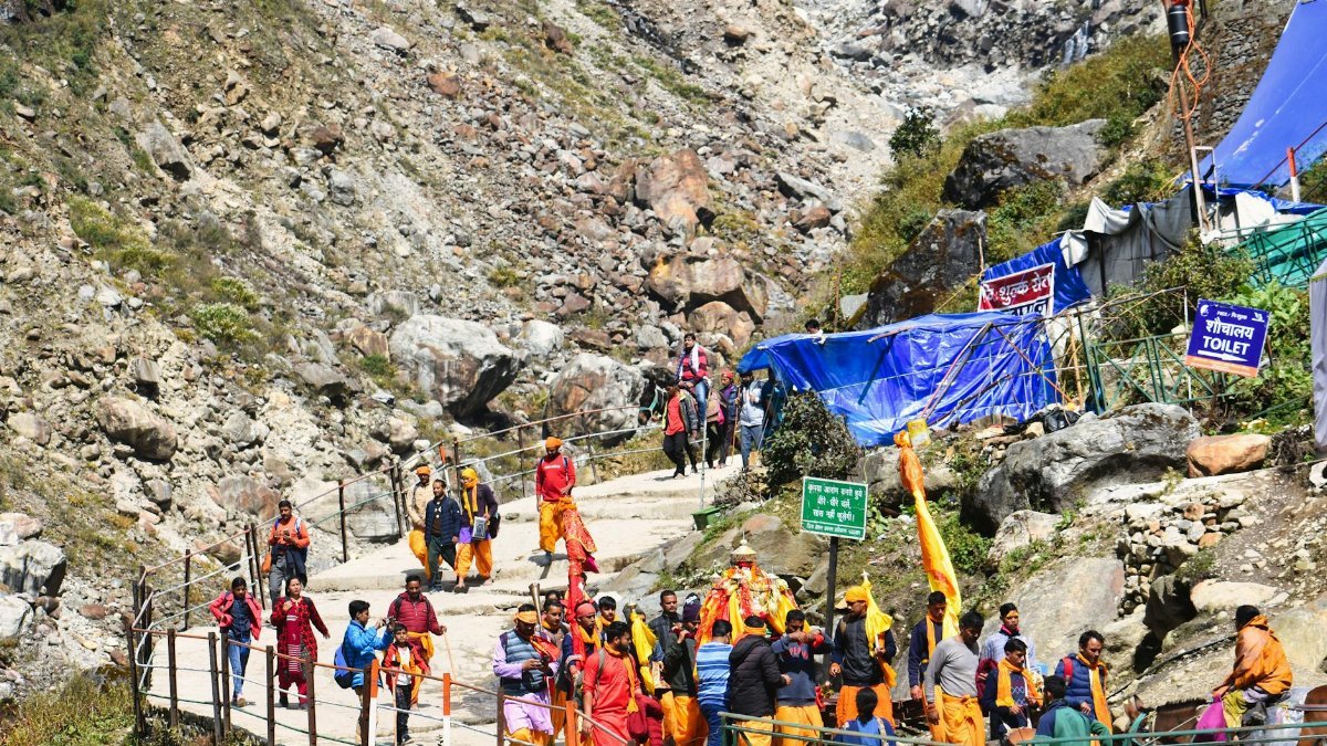 Colorful procession of pilgrims walking along the rocky path in Kedarnath, India.