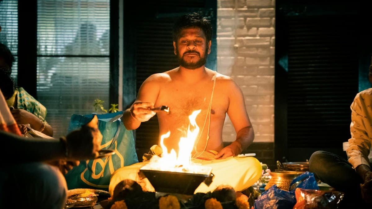 A Hindu priest performing a sacred fire ritual inside a dimly lit room, highlighting spiritual traditions.