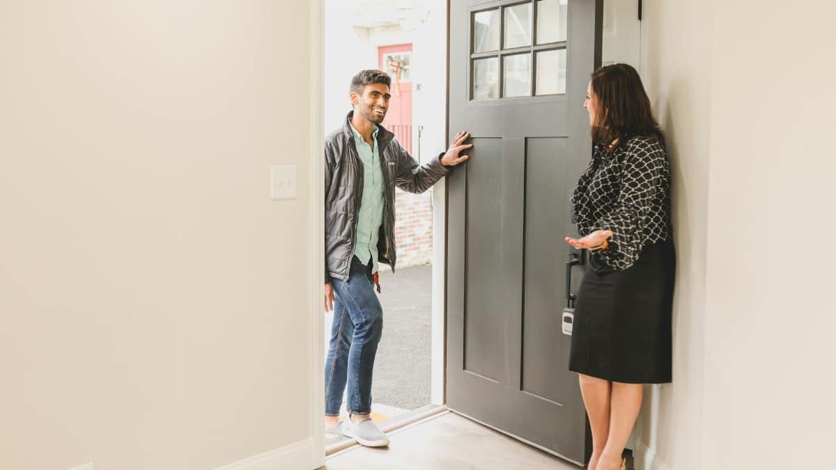 Real estate agent greeting a client at the entrance of a new home, symbolizing a welcoming embrace for potential buyers.