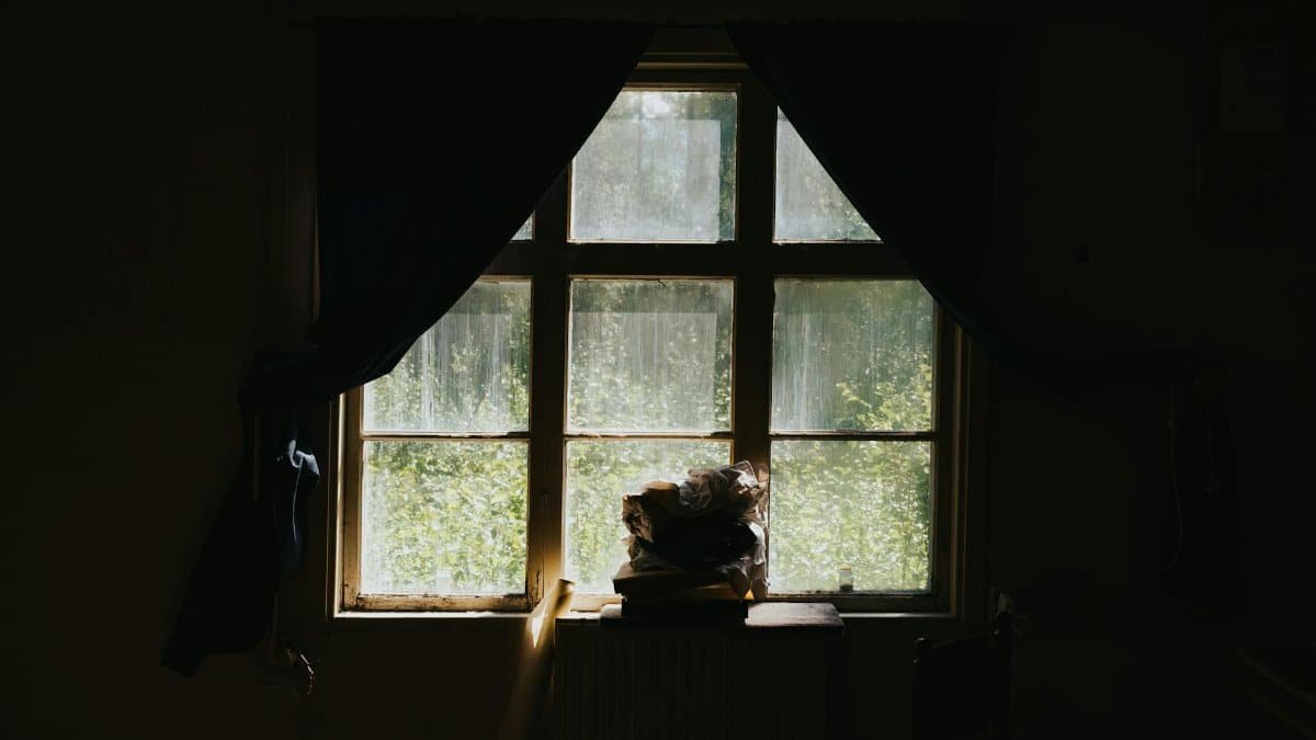 A dimly lit room with sunlight streaming through a rustic window.