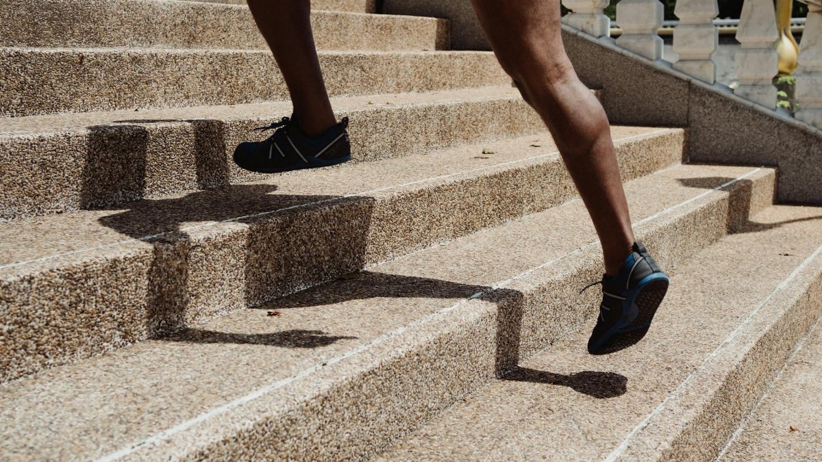 Close-up of a runner's legs ascending stone steps, capturing movement and shadow play.