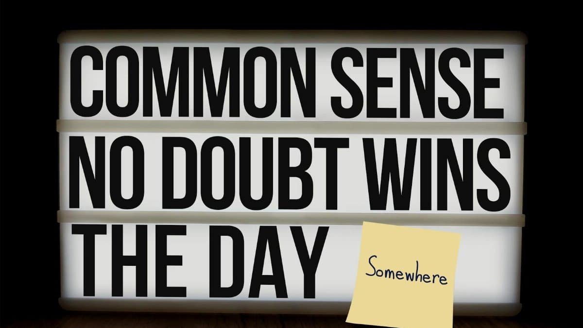 Lightbox with motivational quote 'Common Sense No Doubt Wins the Day' and sticky note on wood grain surface.