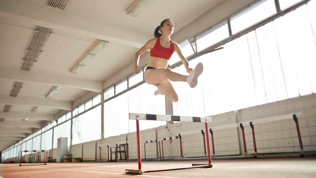 Dynamic action shot of a woman hurdling indoors, showcasing strength and agility.