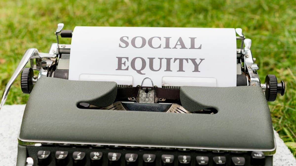 Close-up of a vintage typewriter with 'Social Equity' typed on paper outdoors.