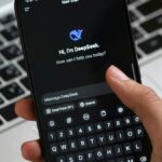 Person interacting with DeepSeek AI chat app on smartphone, focusing on digital innovation and communication.