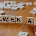 Scrabble-like tiles arranged to spell 'Qwen AI' on a wooden surface, depicting technology concepts.
