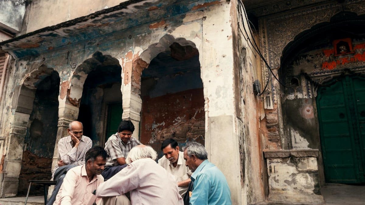 A group of elderly men socializing outside a historic building with rustic architecture.