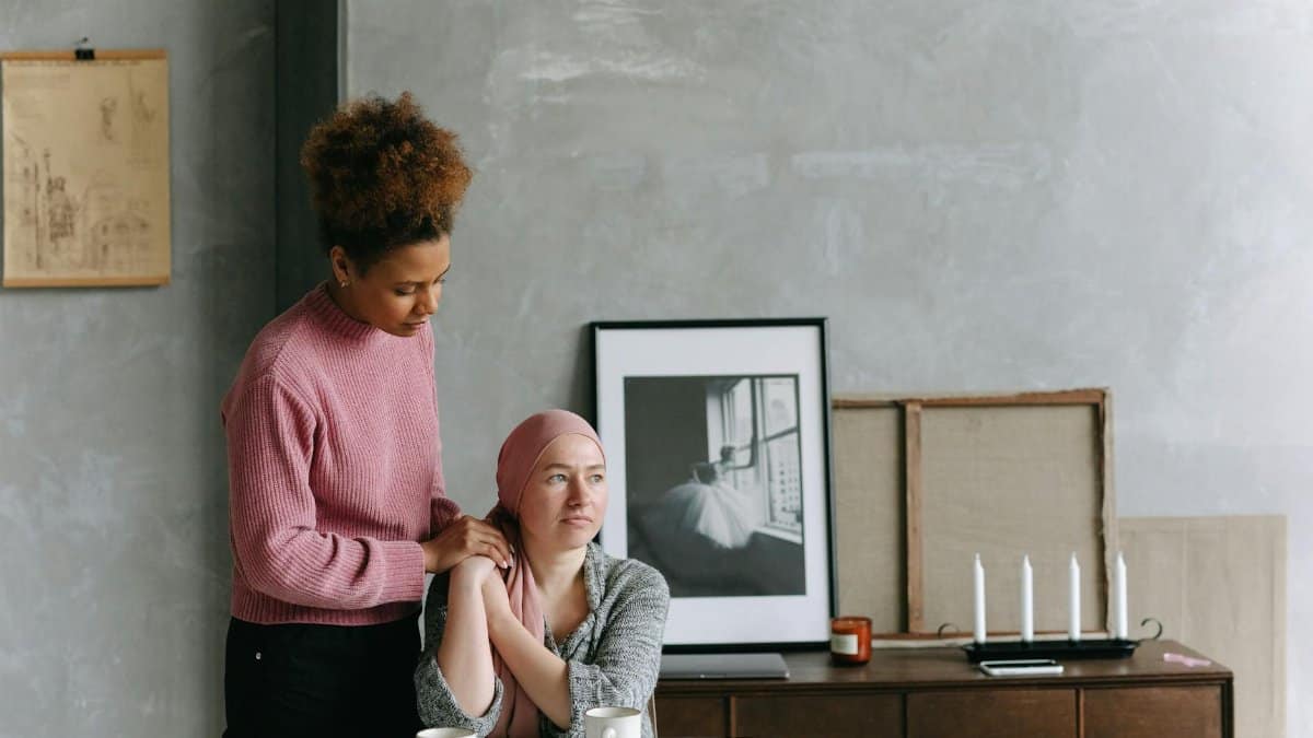 A supportive friend comforts a woman with a headscarf, showing empathy and care.