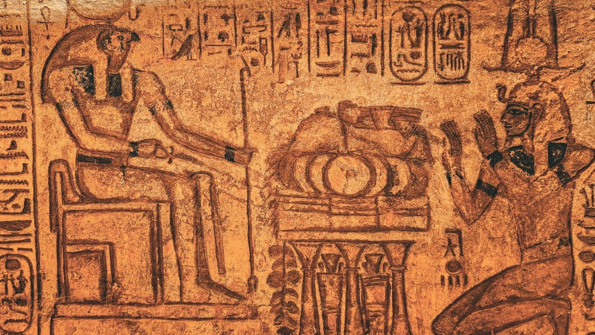Detailed ancient Egyptian wall inscription with hieroglyphics and figures in sepia tones.