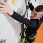 An inspiring image of an amputee man climbing an indoor wall showcasing strength and determination.
