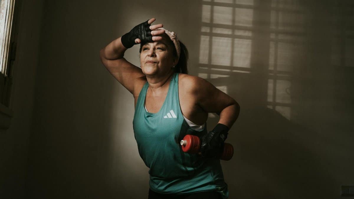 Middle-aged woman working out with a dumbbell indoors. Fitness and healthy lifestyle concept.