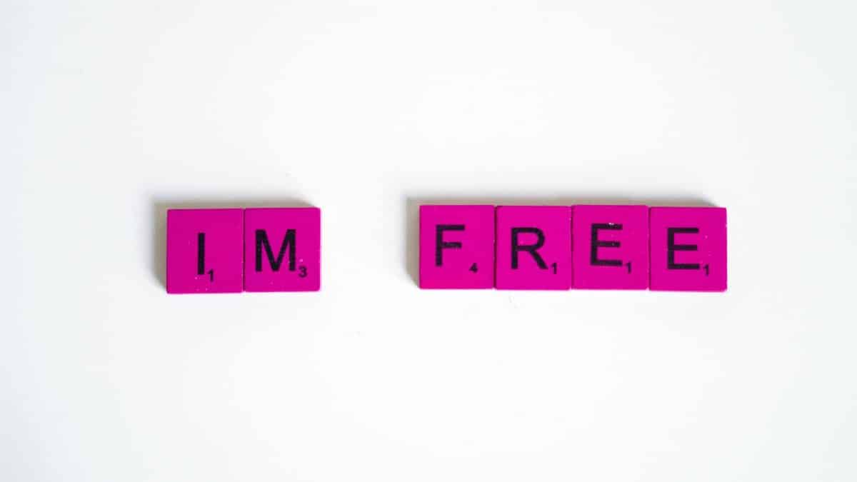 Pink Scrabble tiles arranged to spell 'I'm free' on a white background, conveying freedom.