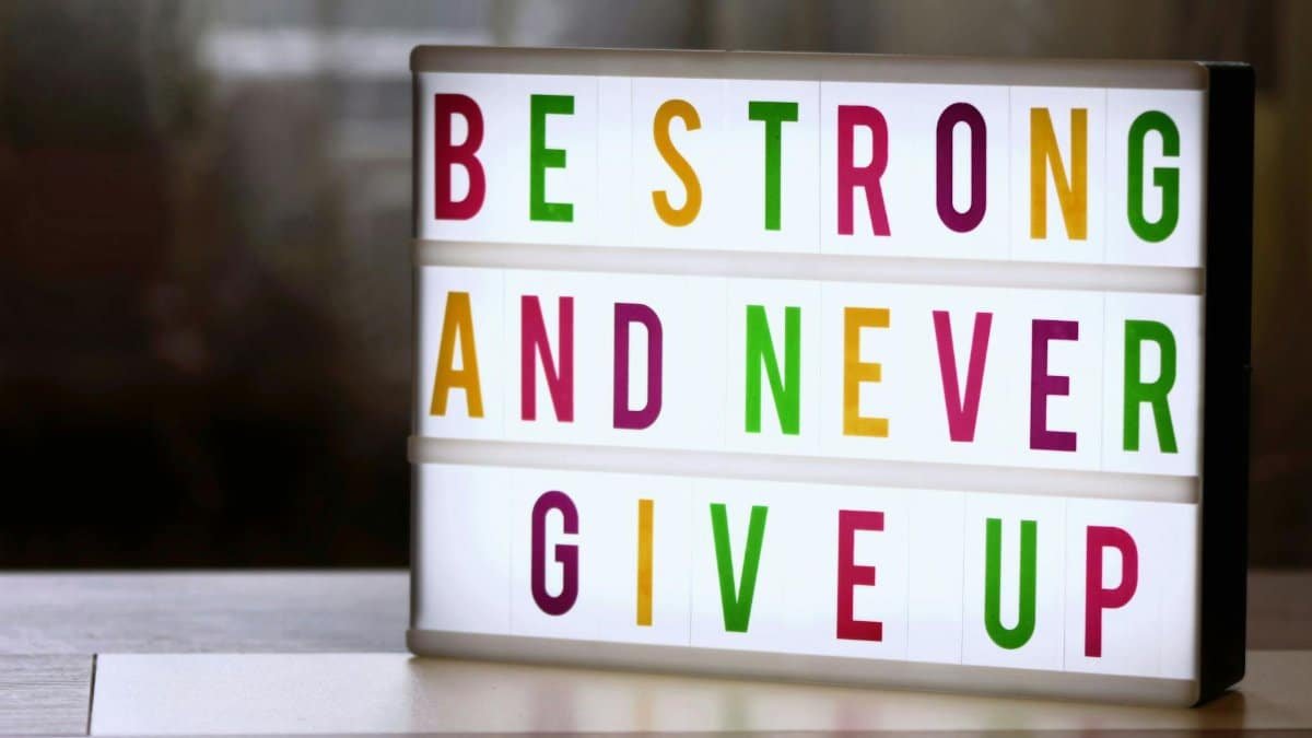 Motivational lightbox sign displaying 'Be Strong and Never Give Up.'