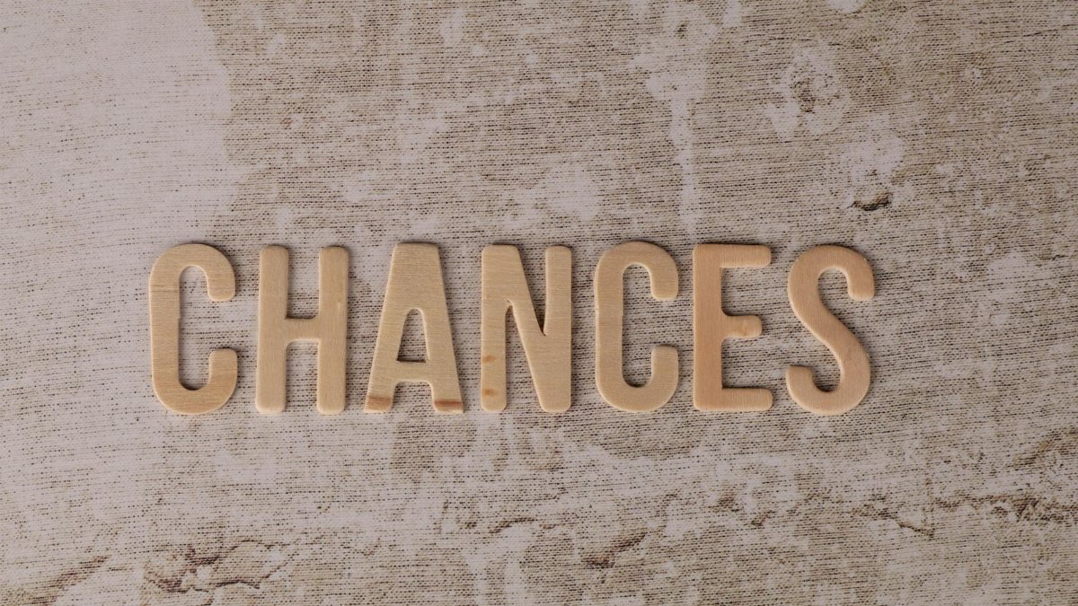 The word 'CHANCES' in wooden letters on a textured, rustic surface.