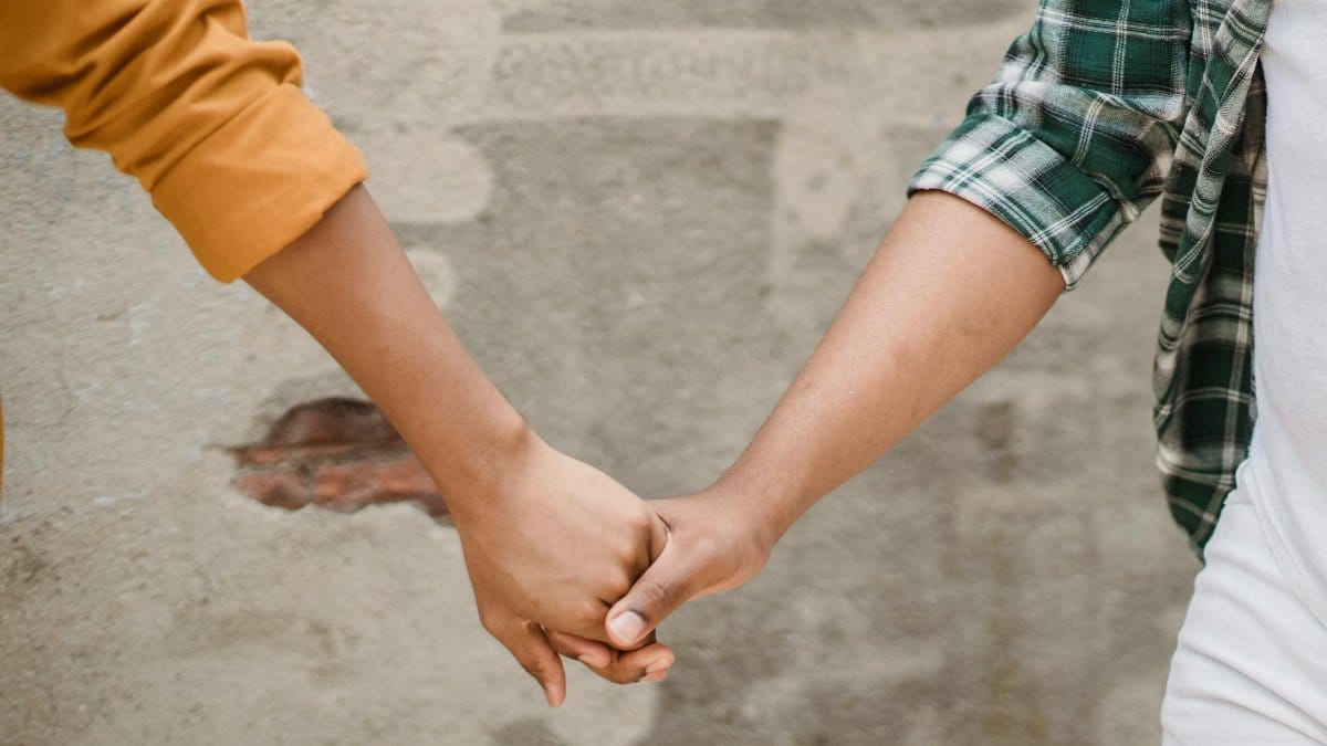 Close-up image of a couple holding hands against a textured wall, symbolizing connection.