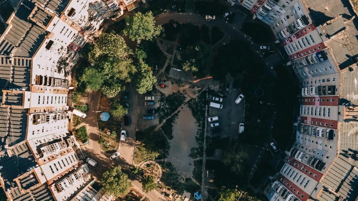 Stunning aerial shot of a circular residential complex surrounded by trees and open spaces.
