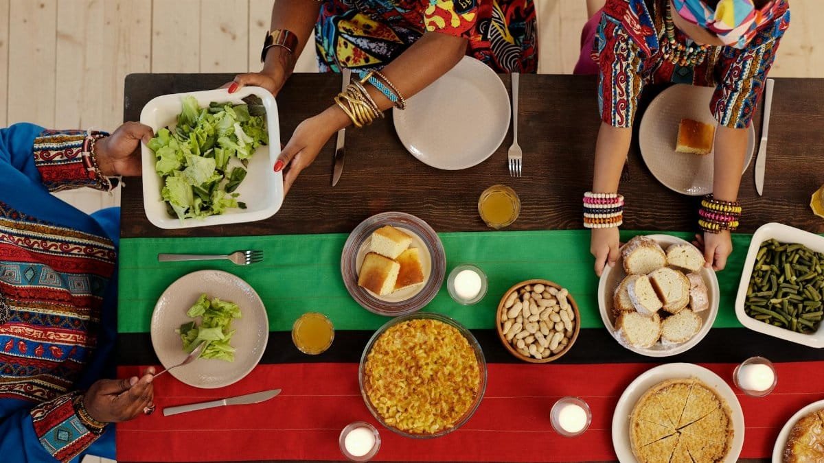 Top view of a family enjoying a Kwanzaa feast with traditional foods and vibrant attire.