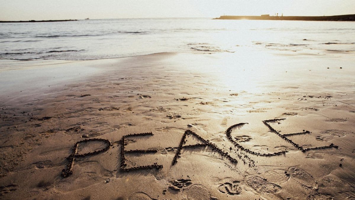 Peace written on a tranquil beach at sunset in the Canary Islands symbolizing tranquility and unity.
