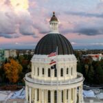A stunning aerial view of the California State Capitol Dome under a colorful sky at dusk.