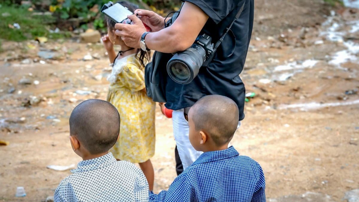 Photographer capturing moments with children in a rustic outdoor scene.