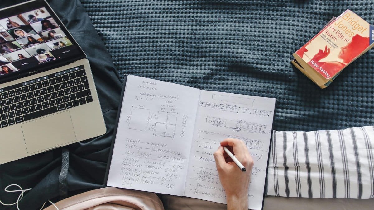 A cozy study setup with a laptop, notebook, and book, depicting remote learning in a relaxed environment.