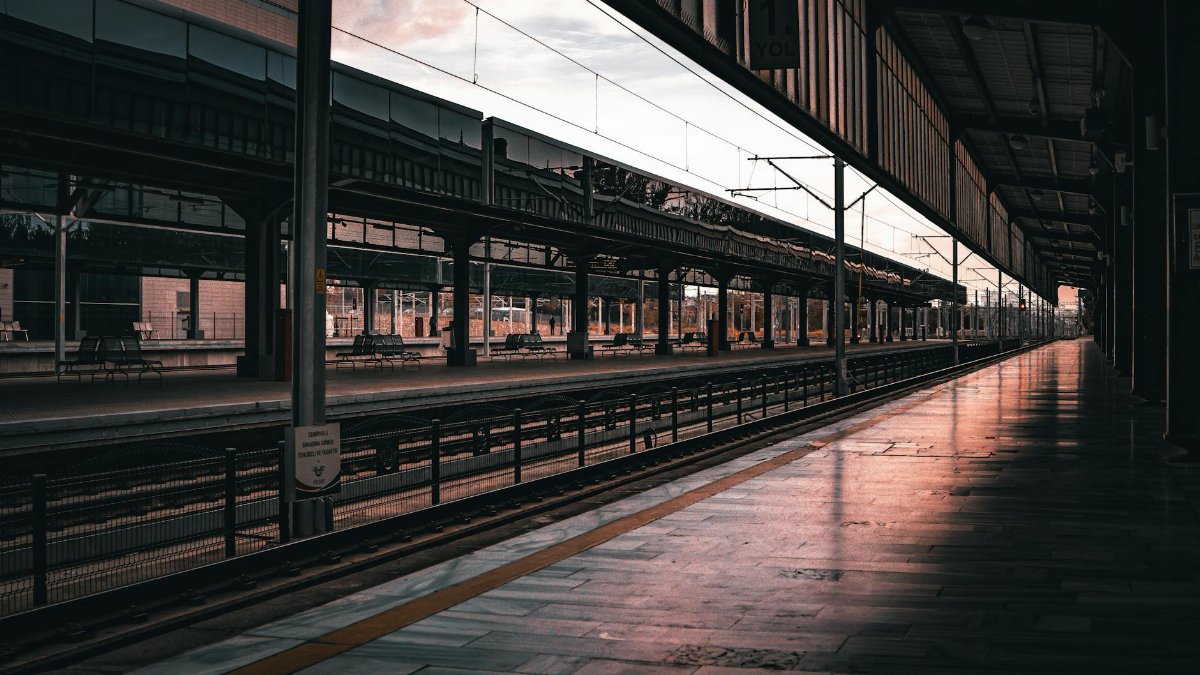 An atmospheric empty train station platform during sunset with serene light reflection.
