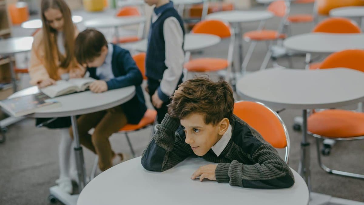 A young child feeling left out in a school classroom surrounded by peers.