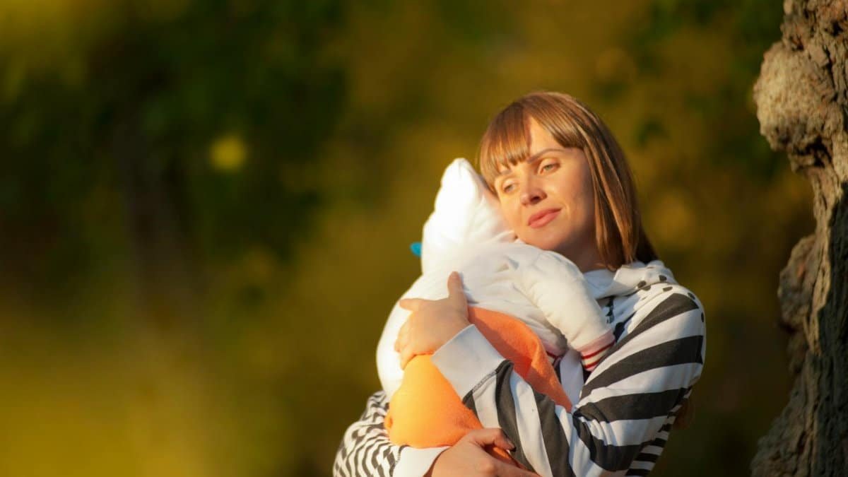 A serene moment of a mother cuddling her baby outdoors during the day.