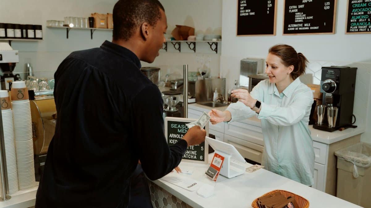 A customer pays for coffee at a café counter, transaction with barista.