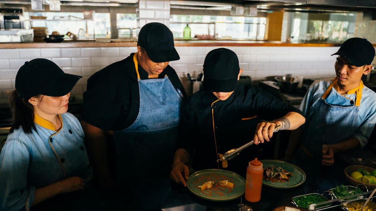Chefs in a professional kitchen preparing and plating gourmet dishes with precision and teamwork.