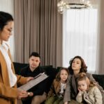 Realtor discusses documents with family sitting on sofa in modern living room.