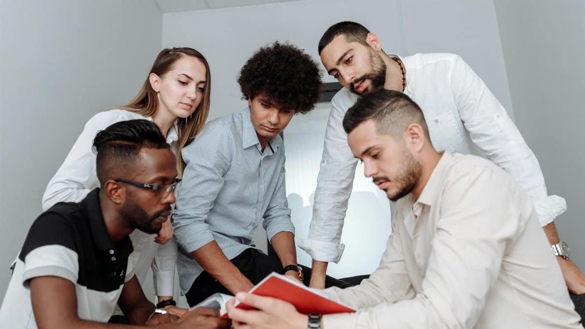 A multicultural team engaged in a collaborative office meeting, discussing ideas around a table.